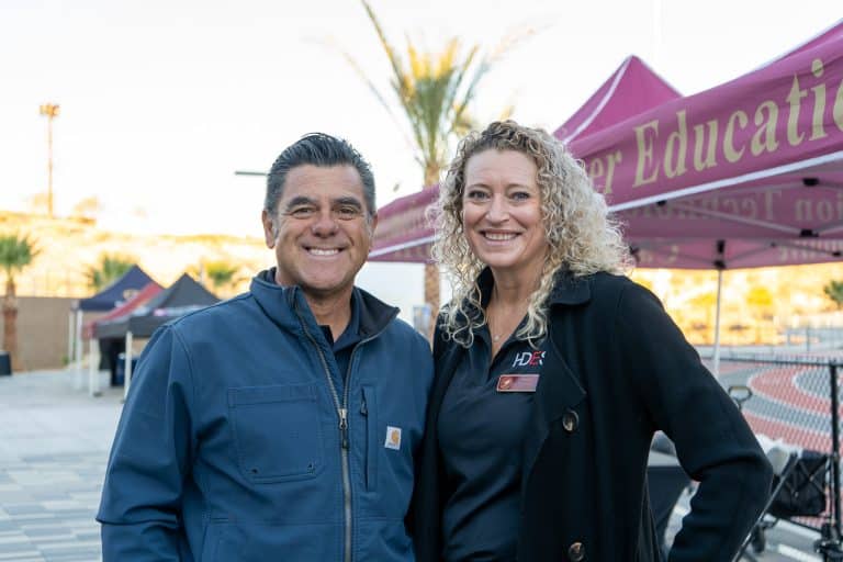 A man and woman smiling together in the exhibitor hall at sunrise during the Summit