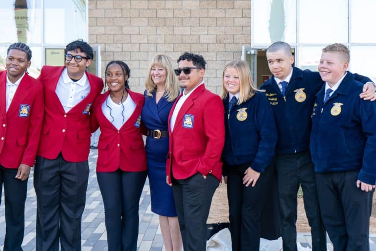 SkillsUSA and FFA students in red and blue jackets standing with a Foundation leader at the Summit