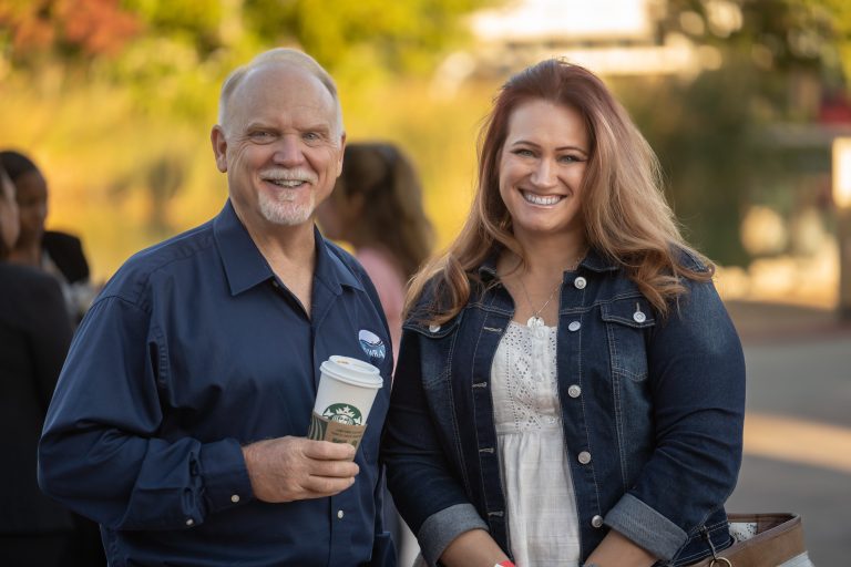 Two attendees smiling with coffee during morning networking at the Summit
