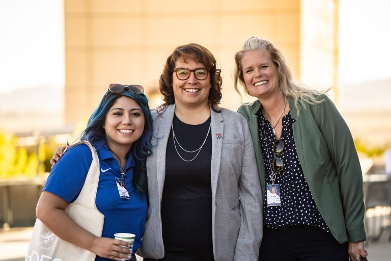 Three women smiling together outdoors during networking at the High Desert Education Summit