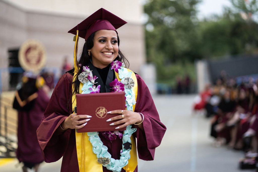 Victor Valley College graduate walking with her diploma at commencement
