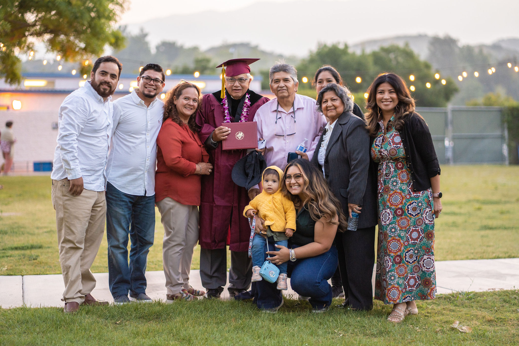 A Victor Valley College graduate embracing family at golden-hour commencement