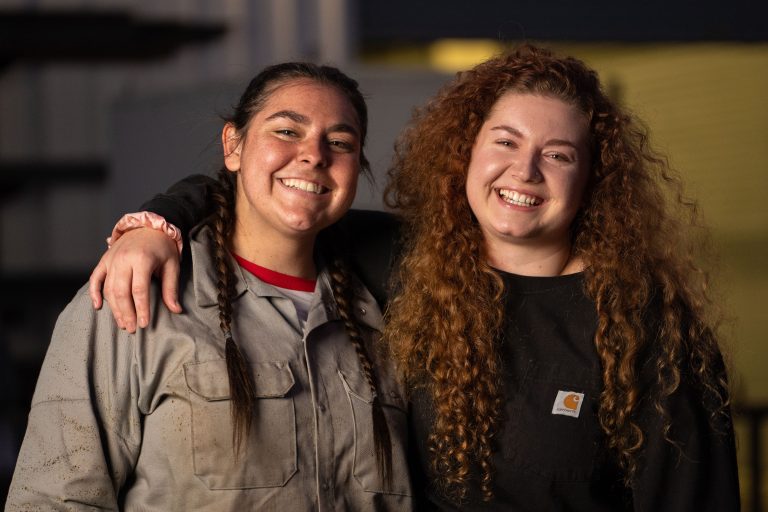 Two Victor Valley College career and technical education students in workwear in the industrial technology shop