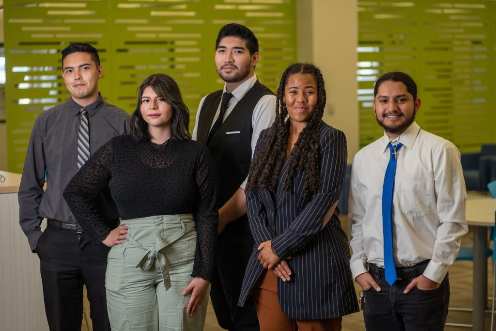 Five Victor Valley College students standing together in a campus building with green glass walls