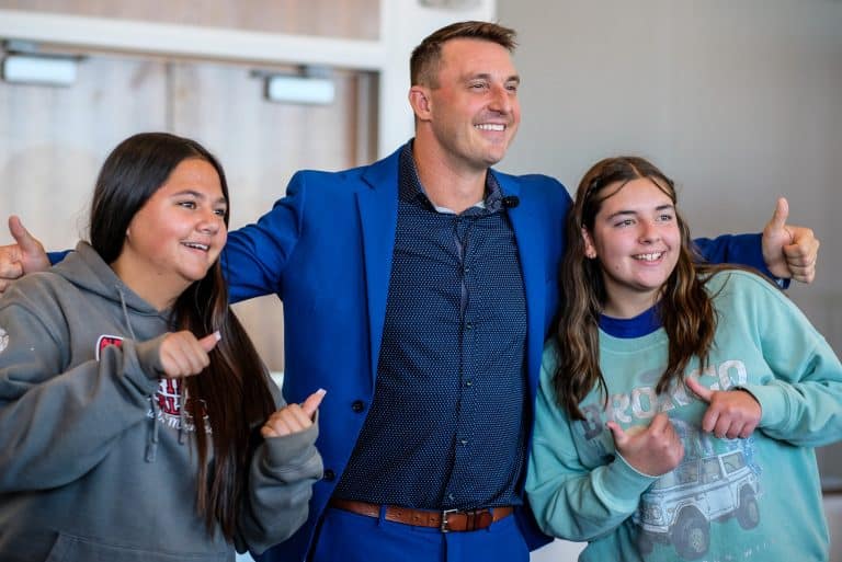 Keynote speaker posing with two young attendees giving a thumbs up at the Summit