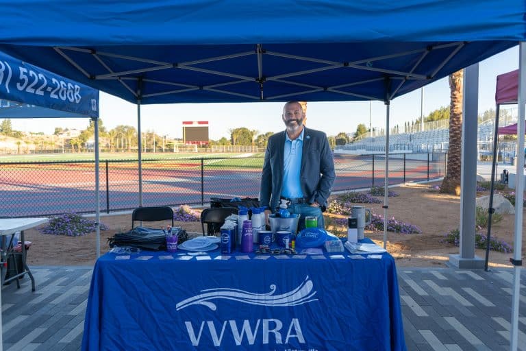 An exhibitor standing at the VVWRA booth in the outdoor exhibitor hall at the High Desert Education Summit