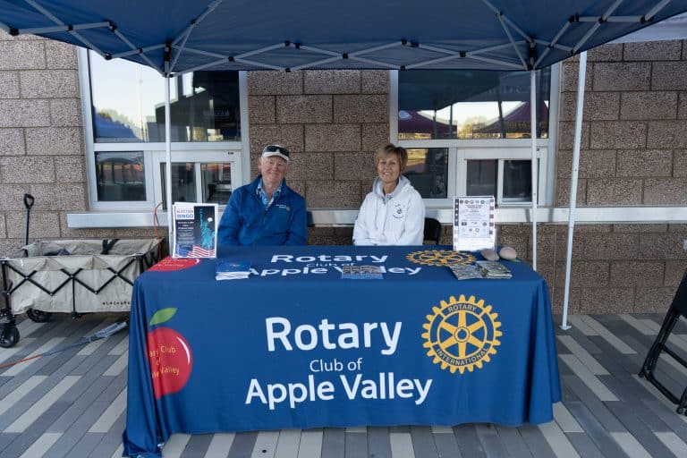 Two volunteers seated at the Rotary Club of Apple Valley exhibitor booth at the Summit