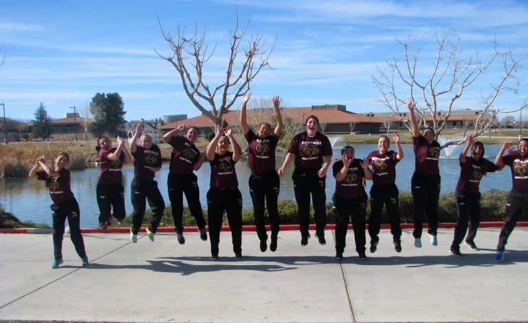 Victor Valley College softball team jumping together by the campus lake