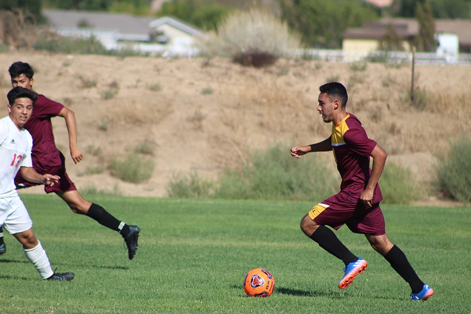 A Victor Valley College soccer player running with the ball during a match