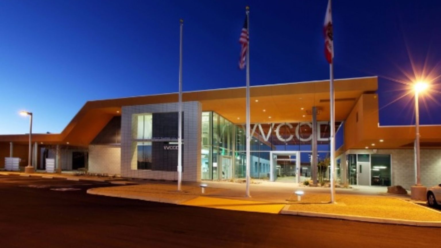 The Victor Valley College Regional Public Safety Training Center at dusk, flags flying outside its illuminated entrance