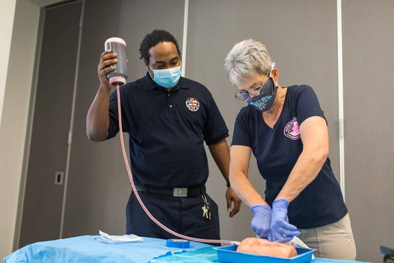 Two Victor Valley College Emergency Medical Services students practising a procedure on a training manikin